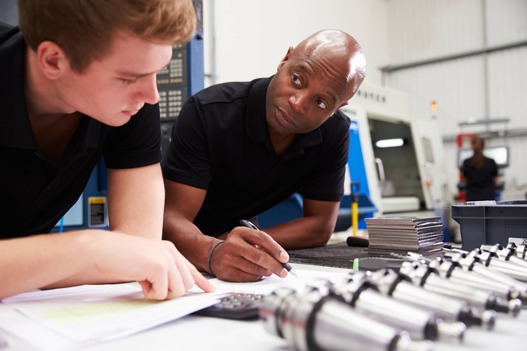 two men writing Engineering Requirements Document in factory